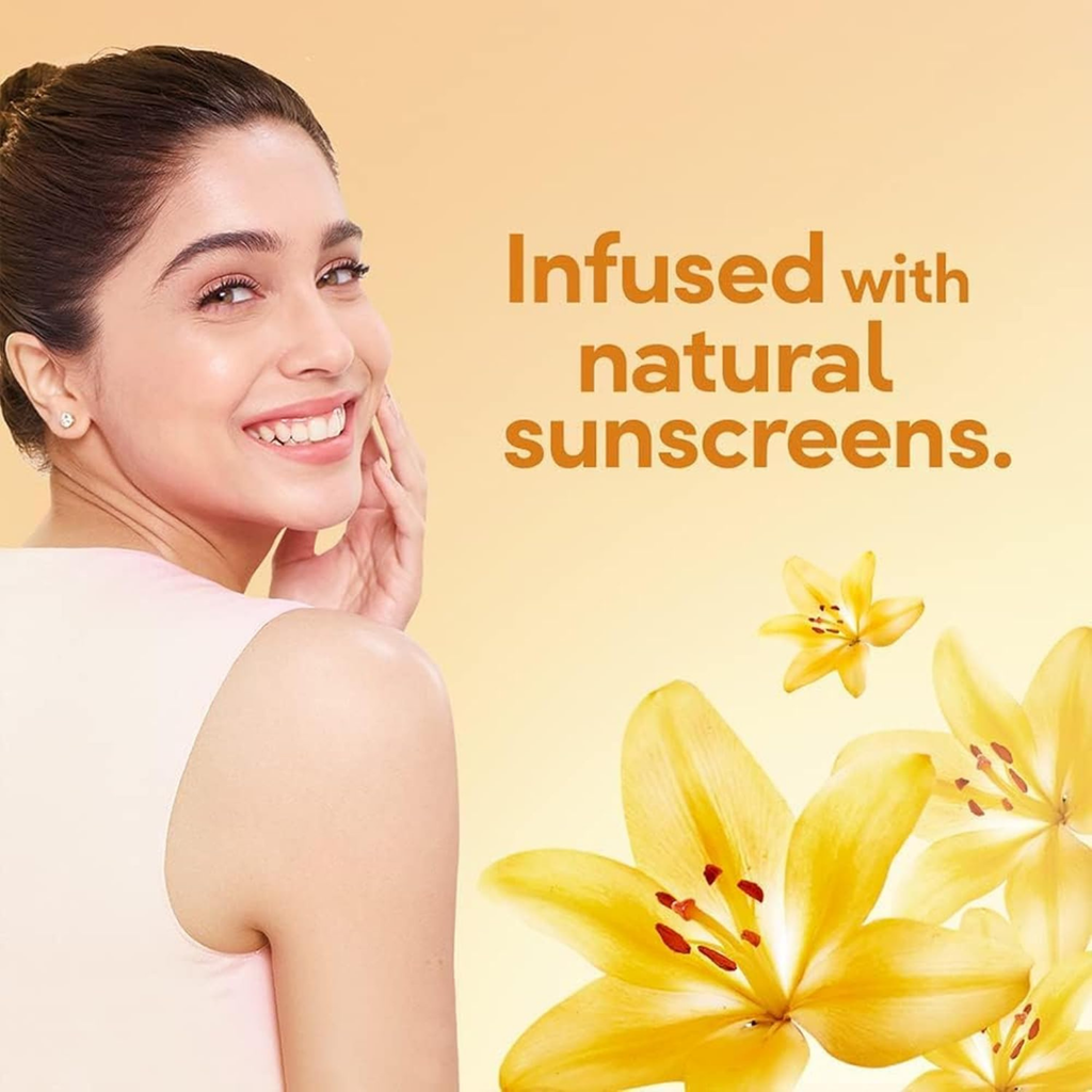 Woman with a radiant smile next to yellow flowers with text 'Infused with natural sunscreens' on a beige background