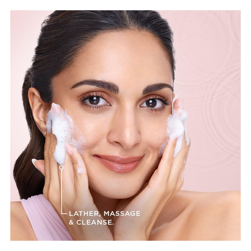 Woman applying a facial cleanser with a pink background