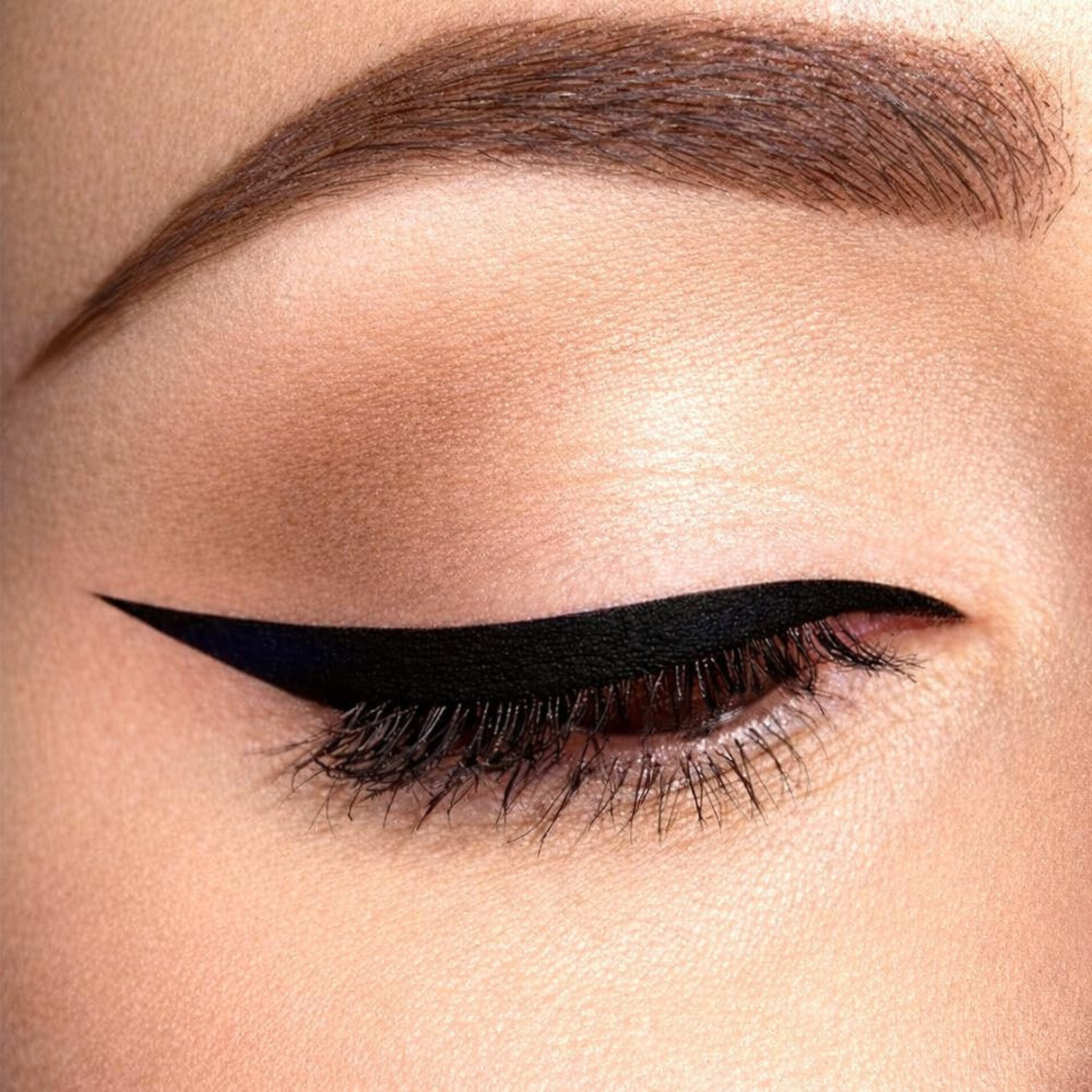 Close-up of a woman's eye with black eyeliner and brown eyebrow.